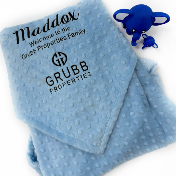 Folded minky baby blanket with a custom embroidered business logo in the corner, showcasing a branded company gift.