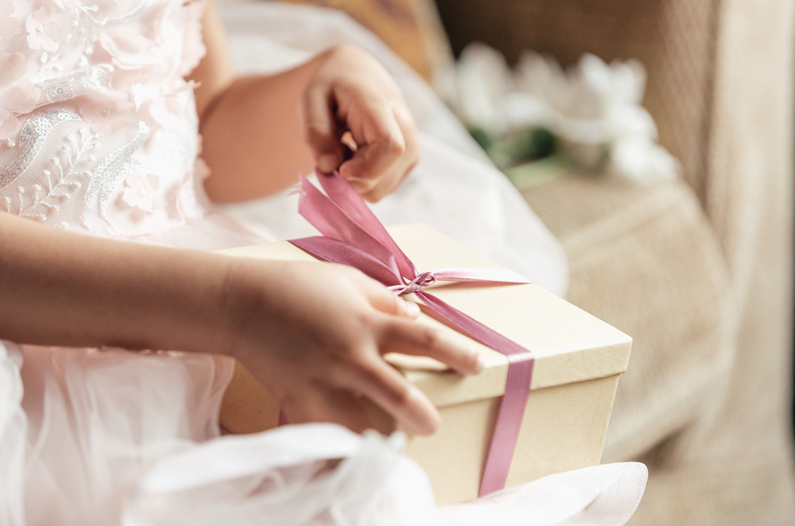 Young girl opening a gift box containing a personalized stuffed animal for a new baby