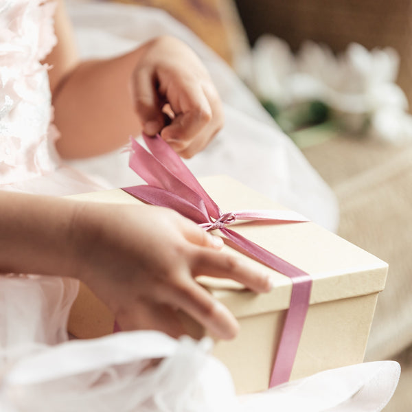 Young girl opening a gift box containing a personalized stuffed animal for a new baby