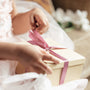 Young girl opening a gift box containing a personalized stuffed animal for a new baby
