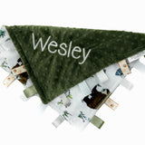 Green textured blanket with 'Wesley' embroidered on it, surrounded by other baby items on a white background.