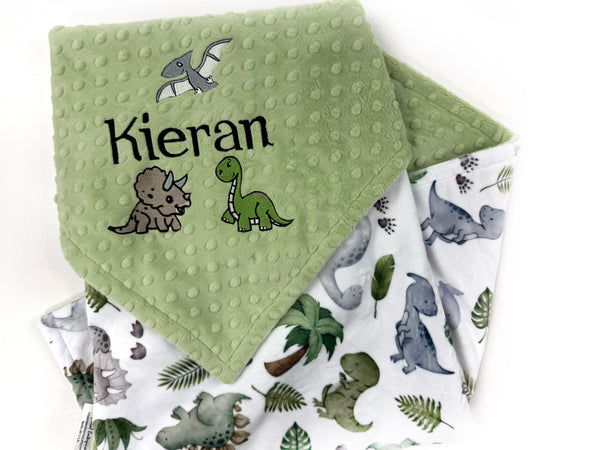 Personalized dinosaur baby blanket with embroidered baby name on sage green dimple minky and colorful dinosaur print backing