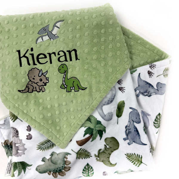 Personalized dinosaur baby blanket with embroidered baby name on sage green dimple minky and colorful dinosaur print backing