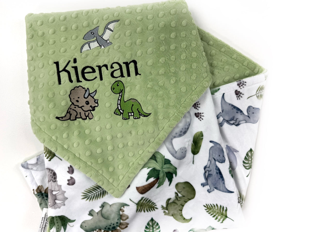 Personalized dinosaur baby blanket with embroidered baby name on sage green dimple minky and colorful dinosaur print backing
