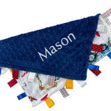 Blue textured blanket with 'Mason' embroidered on it, surrounded by colorful fabric tags.