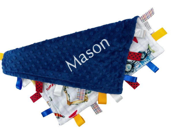 Blue textured blanket with 'Mason' embroidered on it, surrounded by colorful fabric tags.