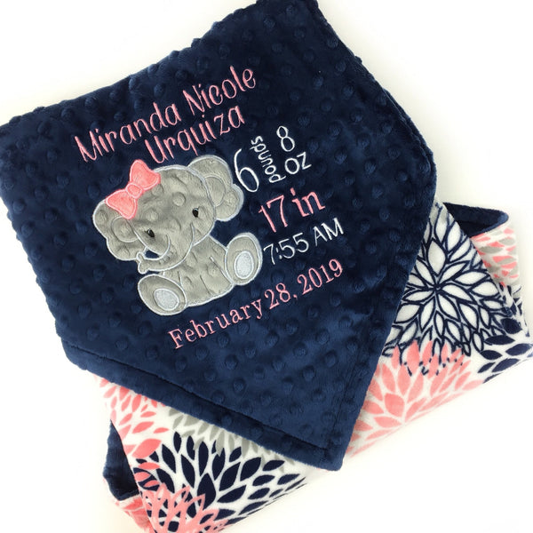 Baby blanket with a gray elephant applique and birth stats in coral and white. Blanket has navy dimple dot on one side with the elephant. The other side is smooth coral and navy floral minky. This is a beautiful soft blanket for baby to snuggle.