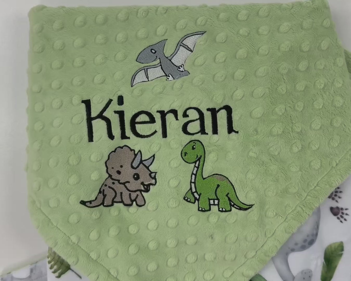 Personalized dinosaur baby blanket with embroidered baby name on sage green dimple minky and colorful dinosaur print backing