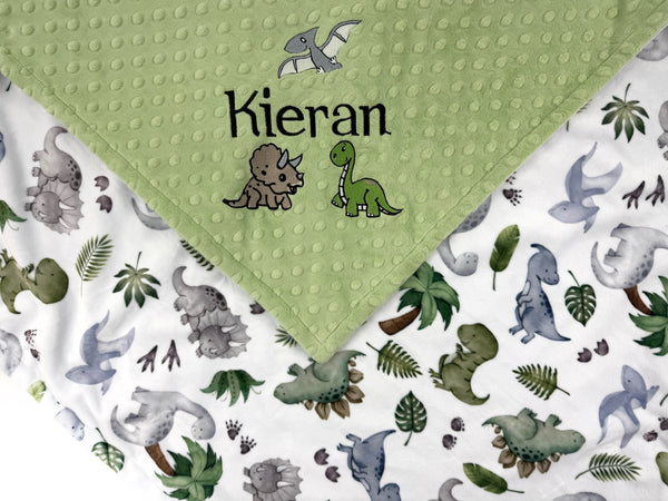Personalized dinosaur baby blanket with embroidered baby name on sage green dimple minky and colorful dinosaur print backing