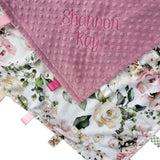 Floral baby blanket with textured pink corner and embroidered name on a white background