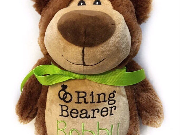 A brown plush teddy bear with a green bow ribbon around its neck, featuring a label with the text 'Ring Bearer Bobby'.